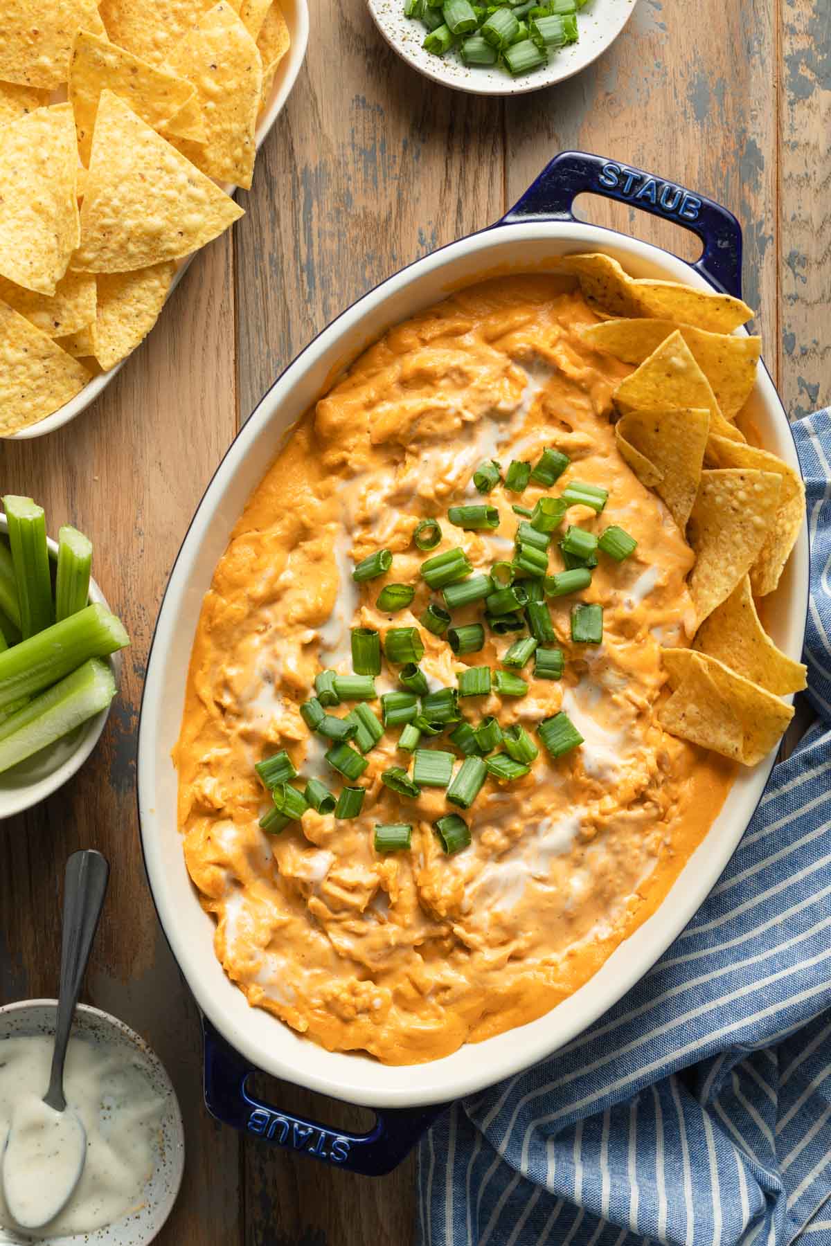 Overhead view of buffalo chicken dips in a dish next to a plate of tortilla chips.