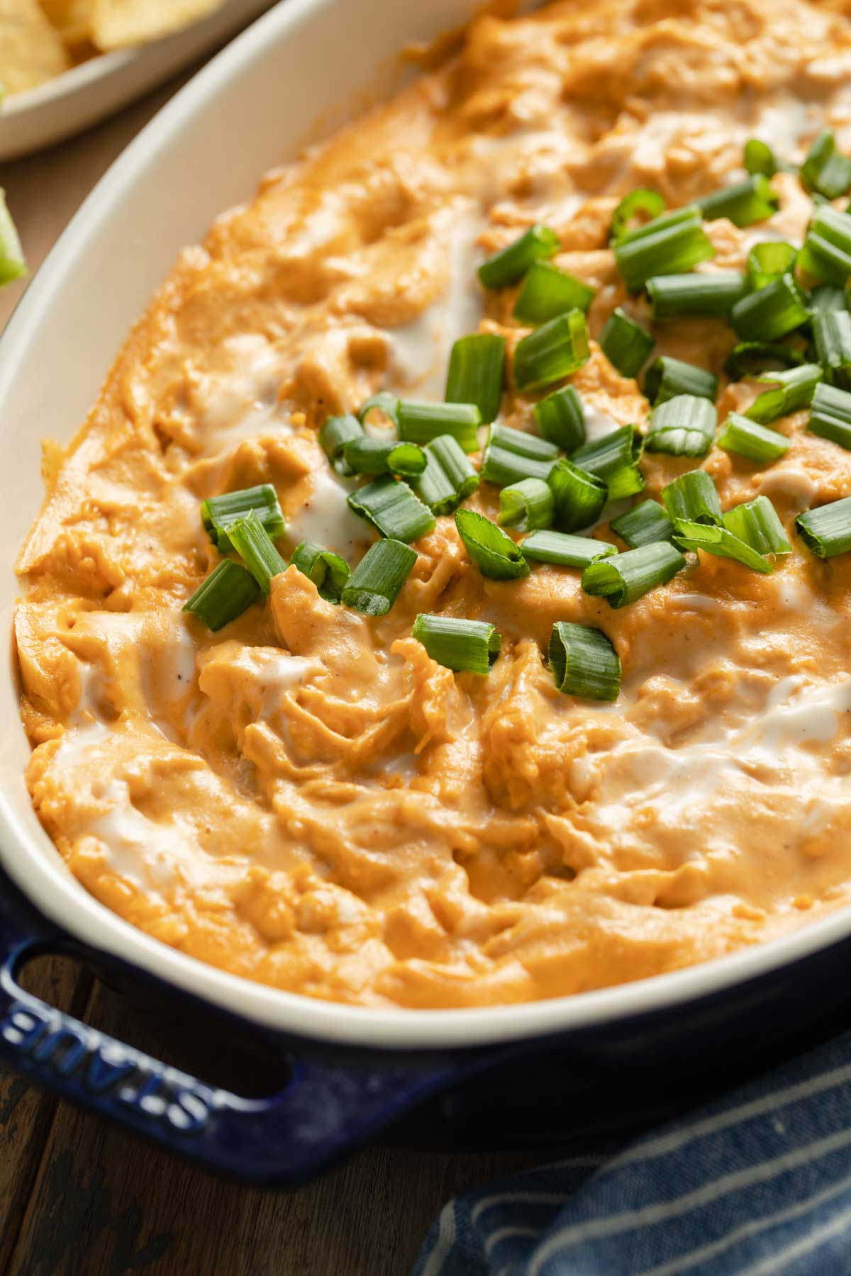 Close up view of buffalo chicken dip topped with chopped green onions.