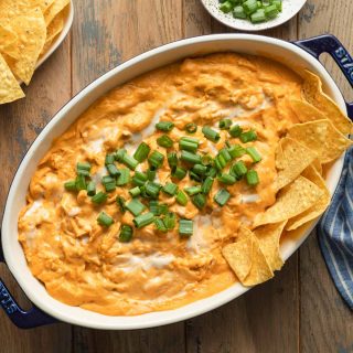 Overhead view of dairy-free buffalo chicken dip in an oval dish and topped with green onions.