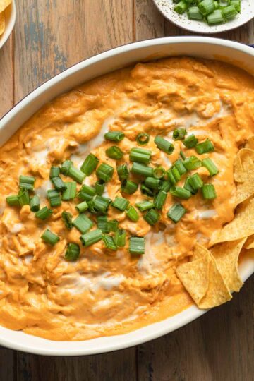 Overhead view of dairy-free buffalo chicken dip in an oval dish and topped with green onions.