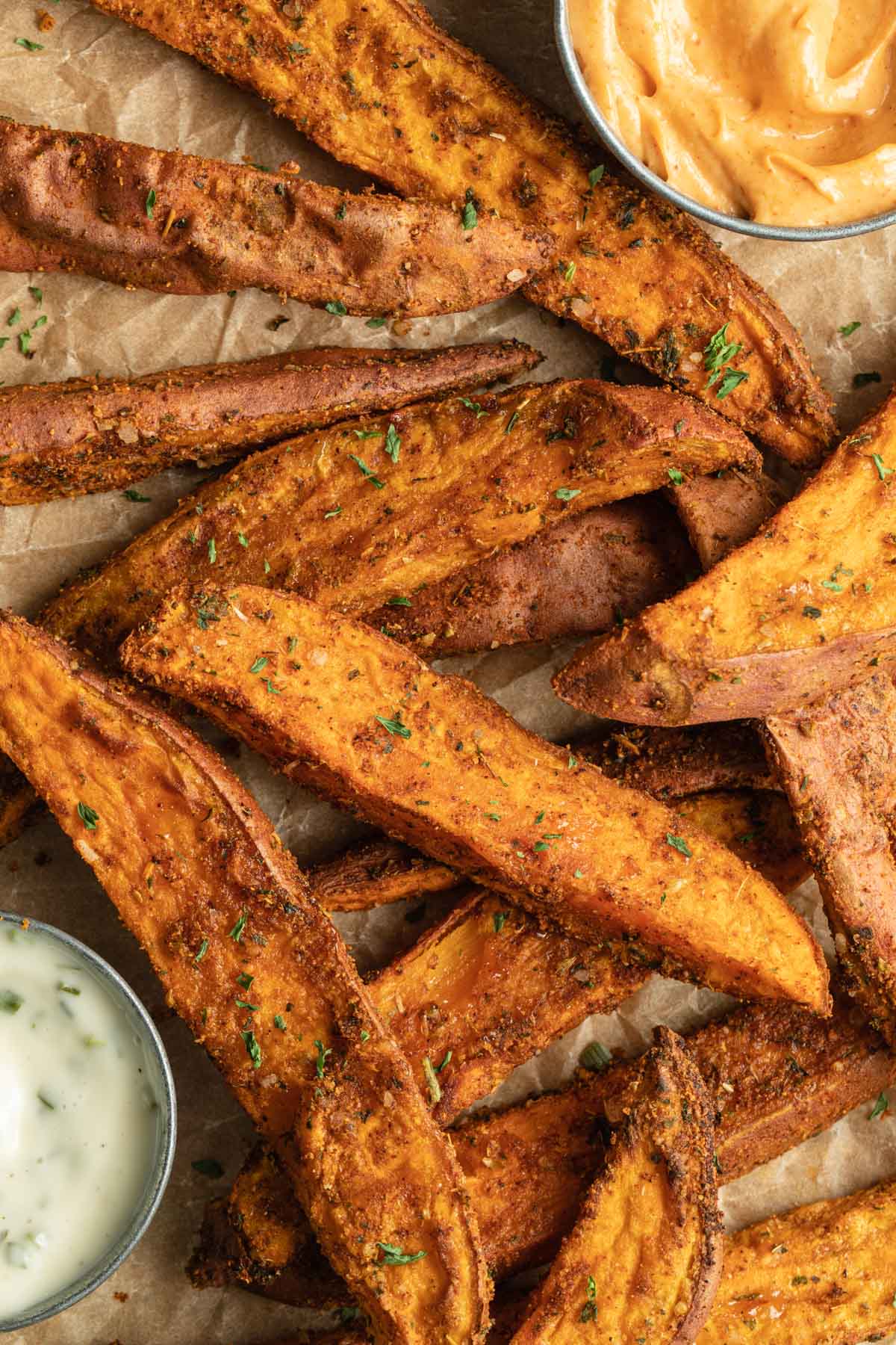 Overhead view of sweet potato wedge fries arranged on brown parchment paper.