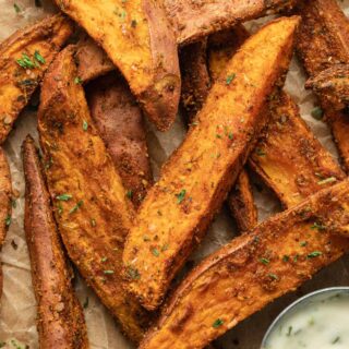 Close up view of air fryer sweet potato wedges arranged on brown parchment paper.