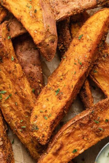 Close up view of air fryer sweet potato wedges arranged on brown parchment paper.