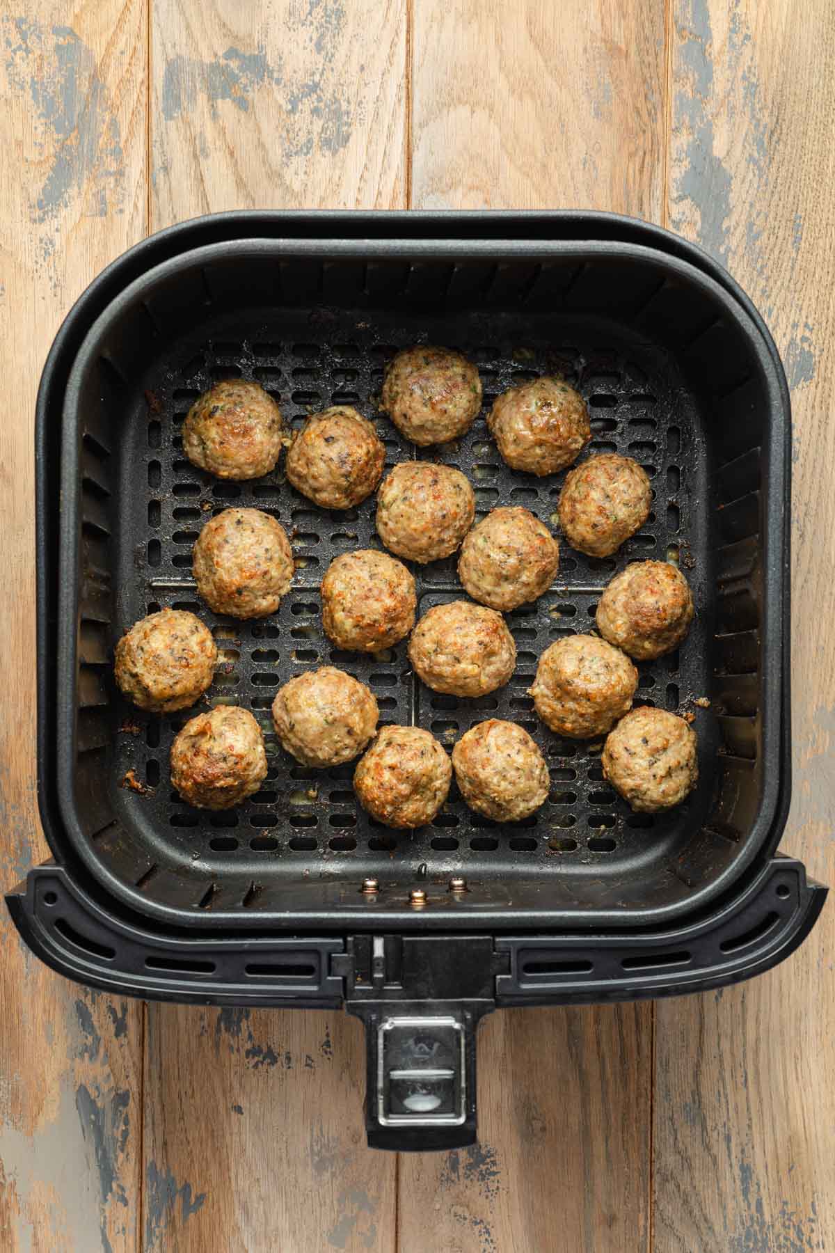 Cooked turkey meatballs in an air fryer basket.