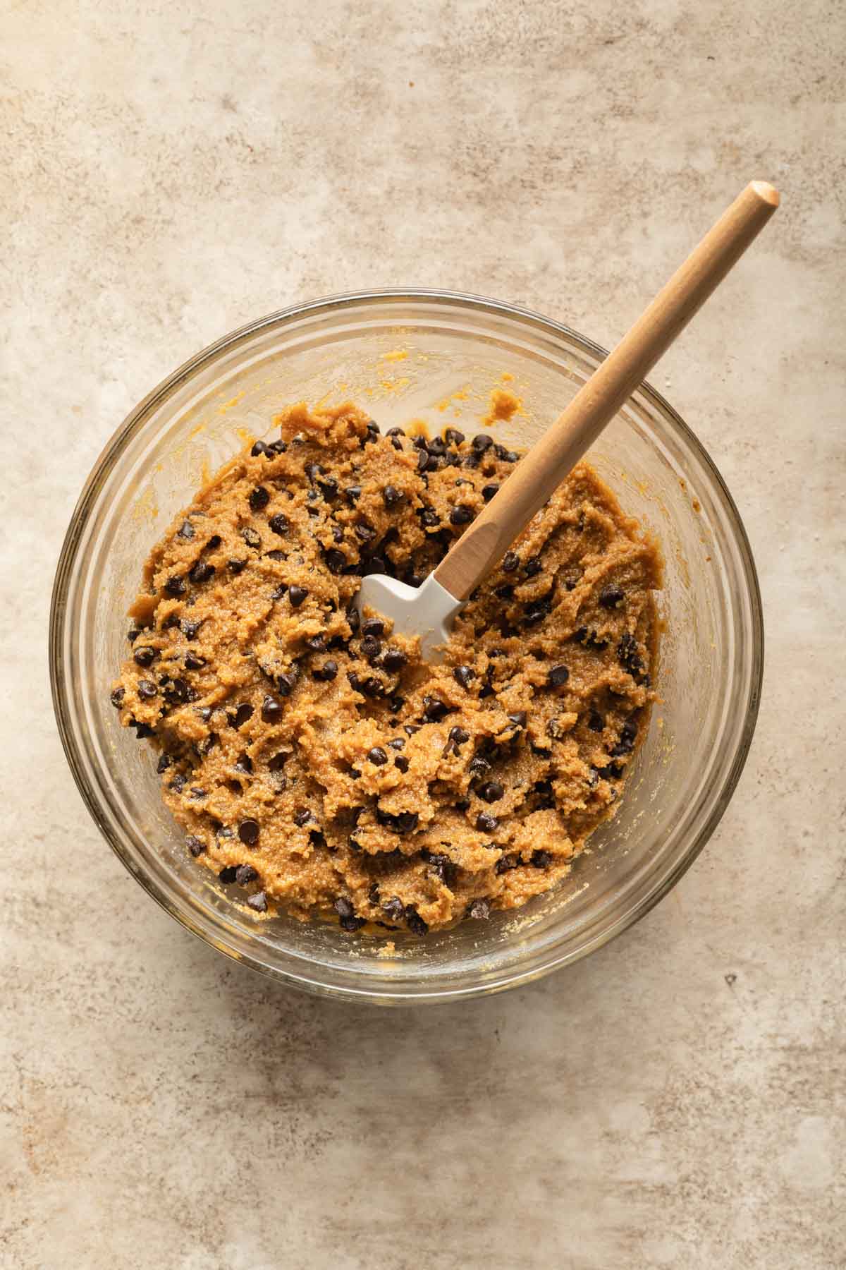 Cookie dough in a glass bowl with a spatula.