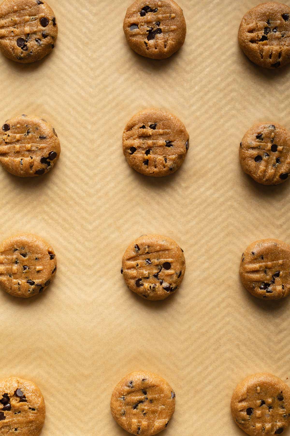 Flattened cookie dough balls on a baking sheet.