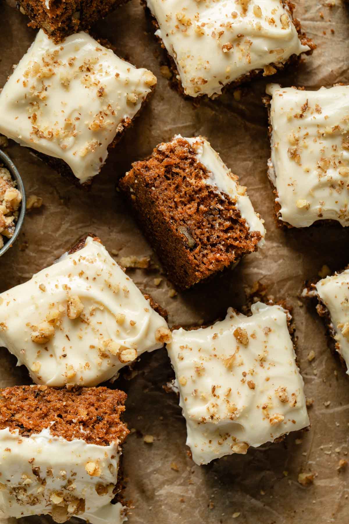 Carrot cake cut into squares and arranged on a sheet of parchment paper.