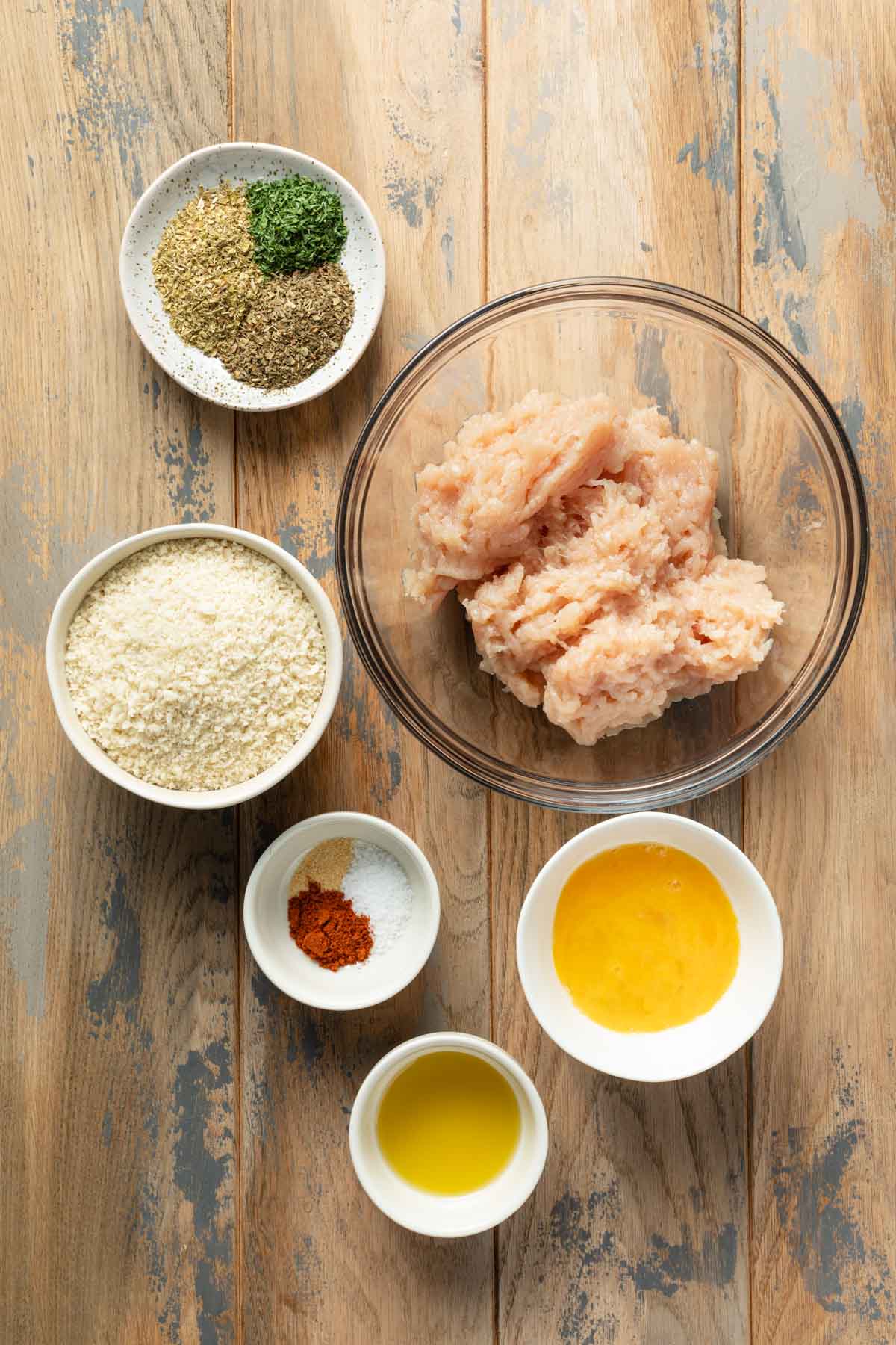 Ingredients to make air fryer chicken patties arranged individually on a wooden surface.