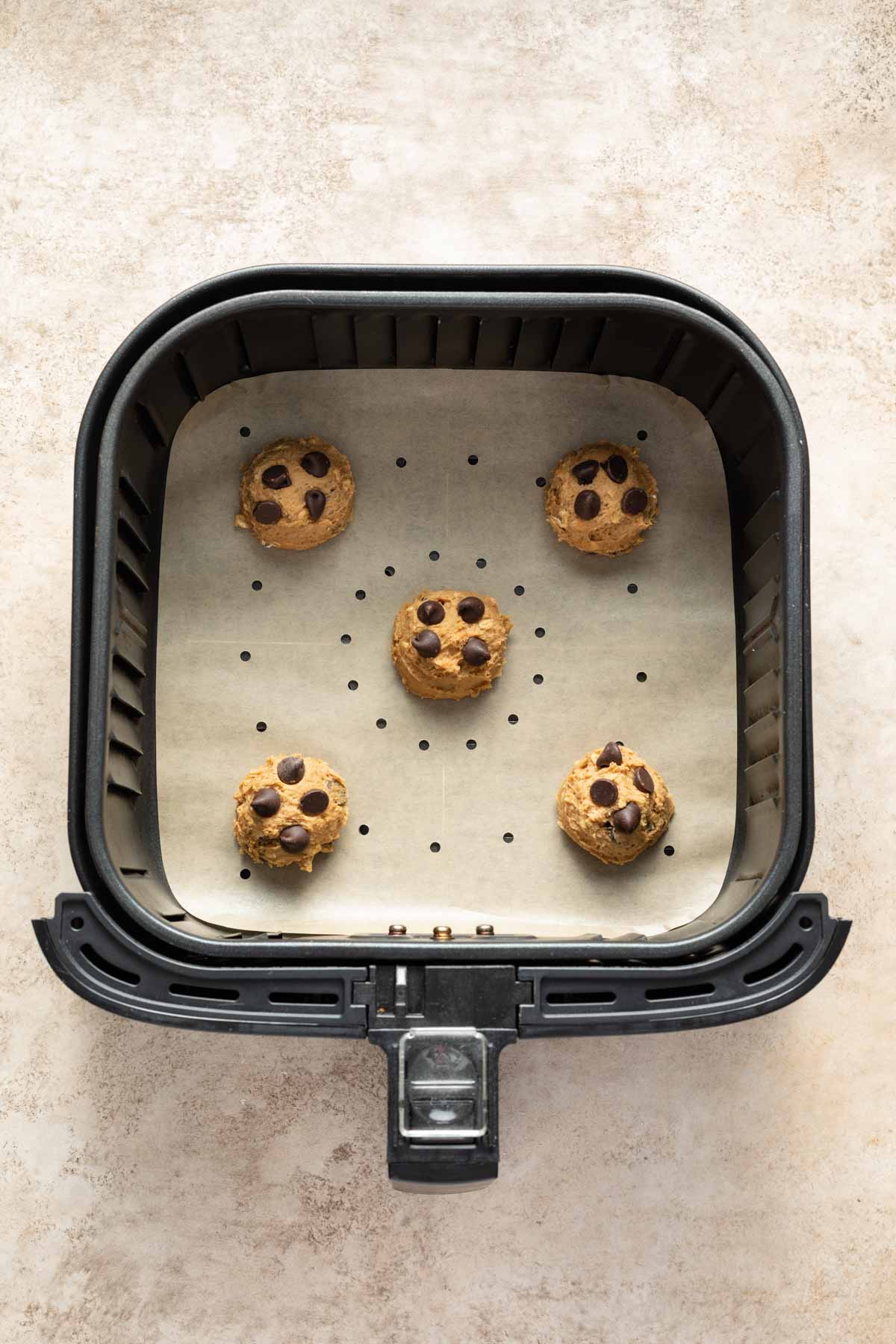 Cookie dough balls in an air fryer basket.