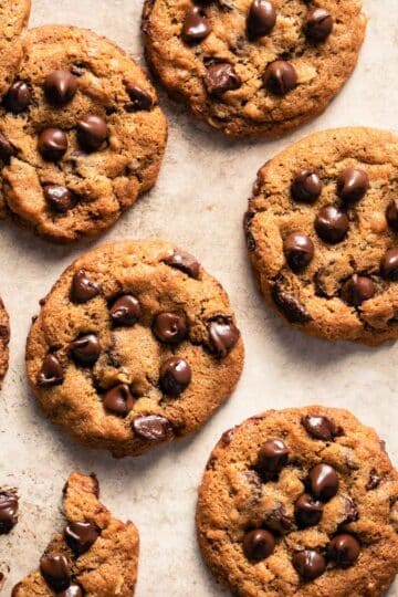 Overhead view of air fryer chocolate chip cookies arranged on a beige surface.