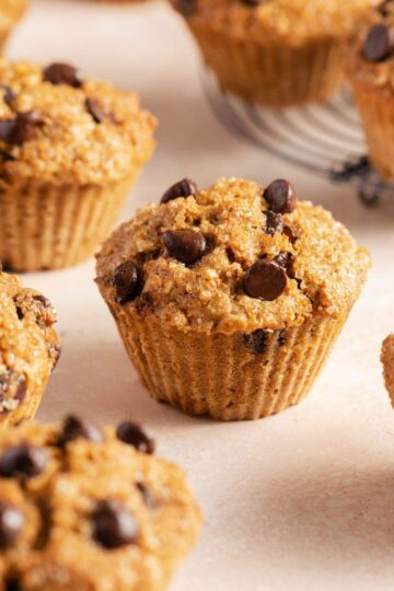 Air fryer muffins with chocolate chips arranged on a pink surface.
