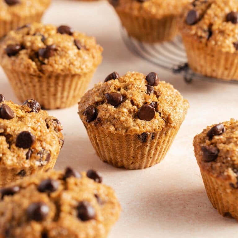 Air fryer muffins with chocolate chips arranged on a pink surface.