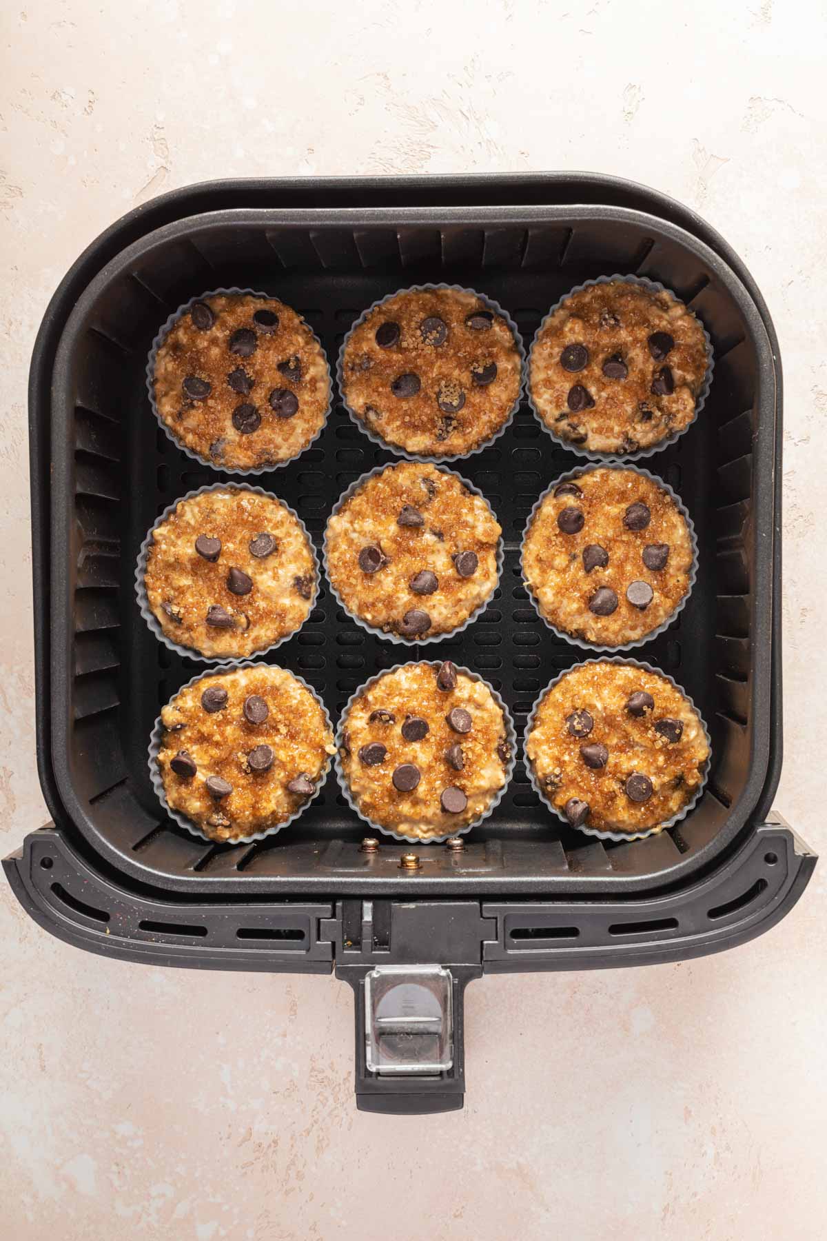 Silicone muffin cups filled with batter and arranged in the air fryer basket.