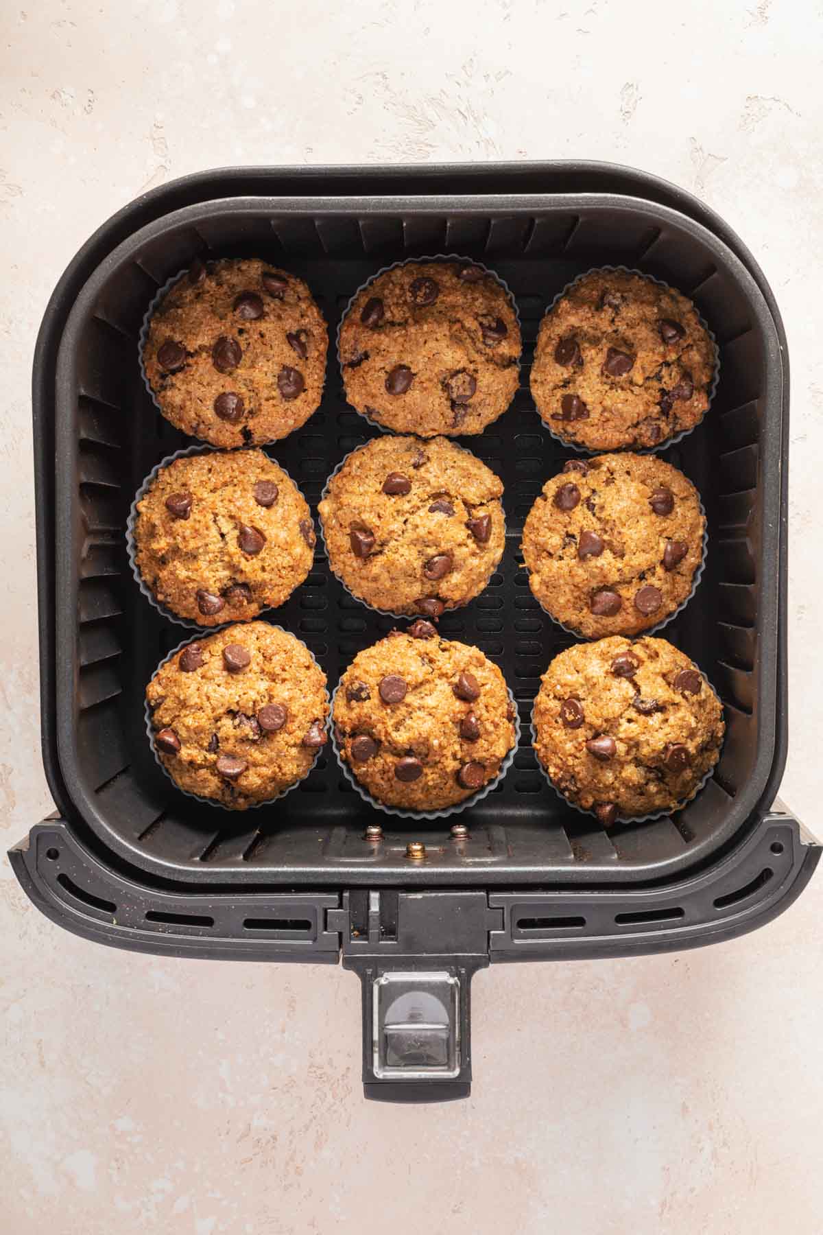 Baked chocolate chip muffins in an air fryer basket.