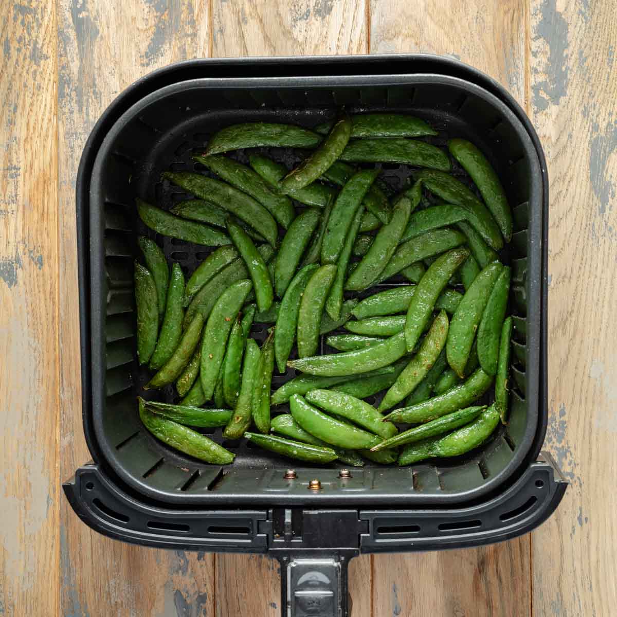 Air fried snap peas in air fryer basket.