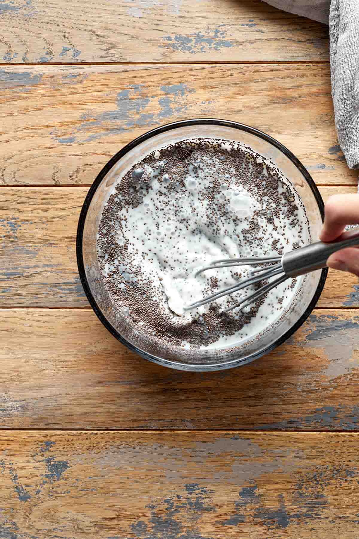 Chia seeds being whisked together with milk and maple syrup.