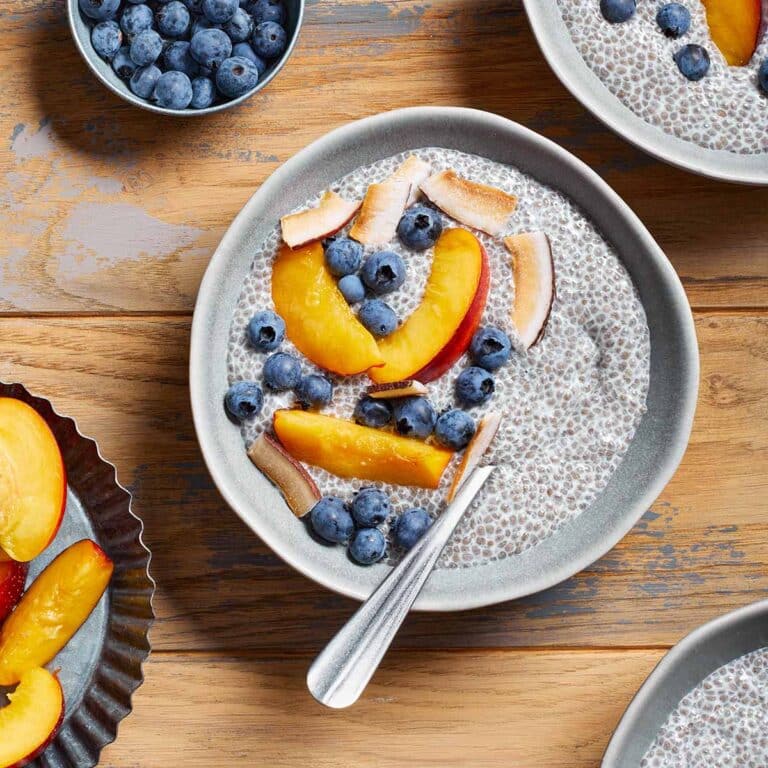 Oat milk chia pudding in a bowl with nectarine slices and blueberries on top.