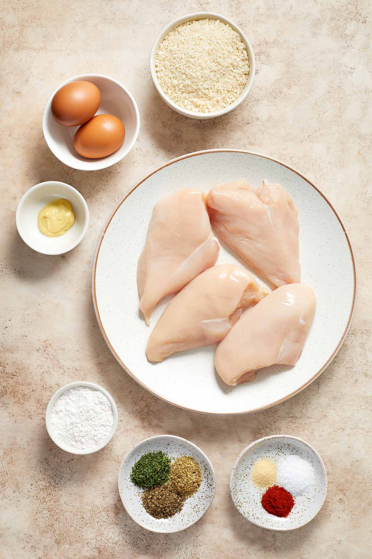 Ingredients to make air fryer chicken schnitzel arranged in individual dishes.