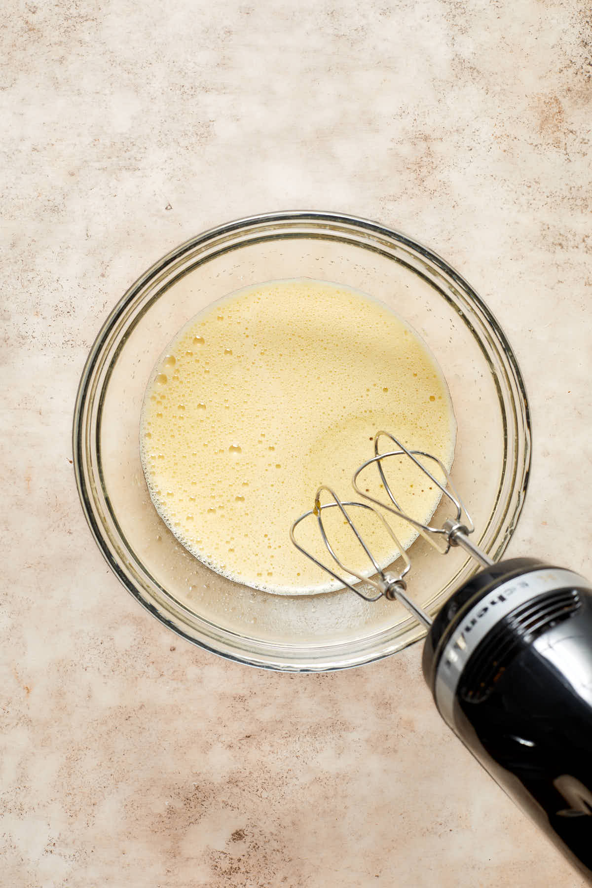 Eggs and sugar whipped together in a glass bowl.