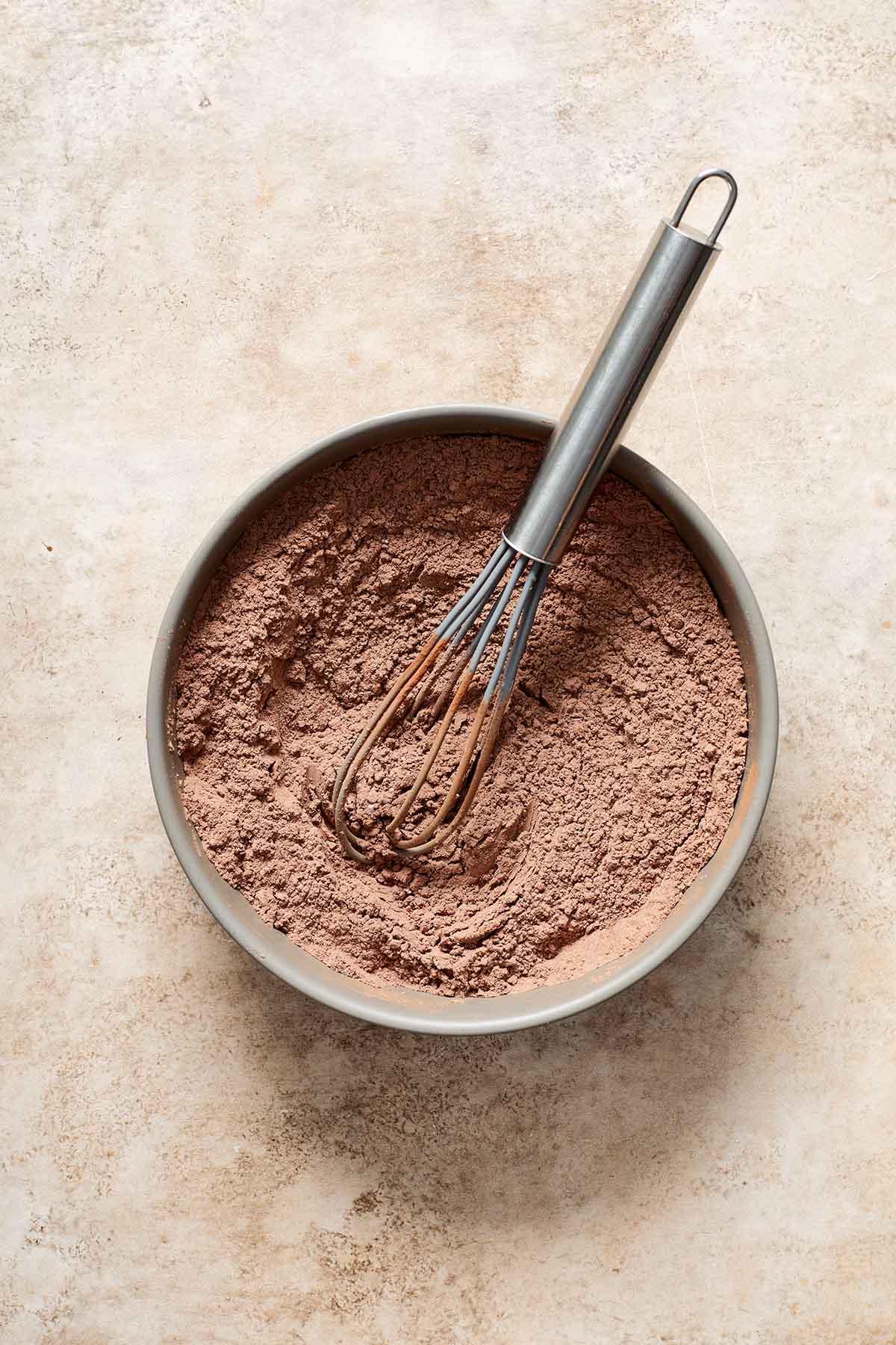 Dry ingredients for cupcakes whisked together in a grey bowl.