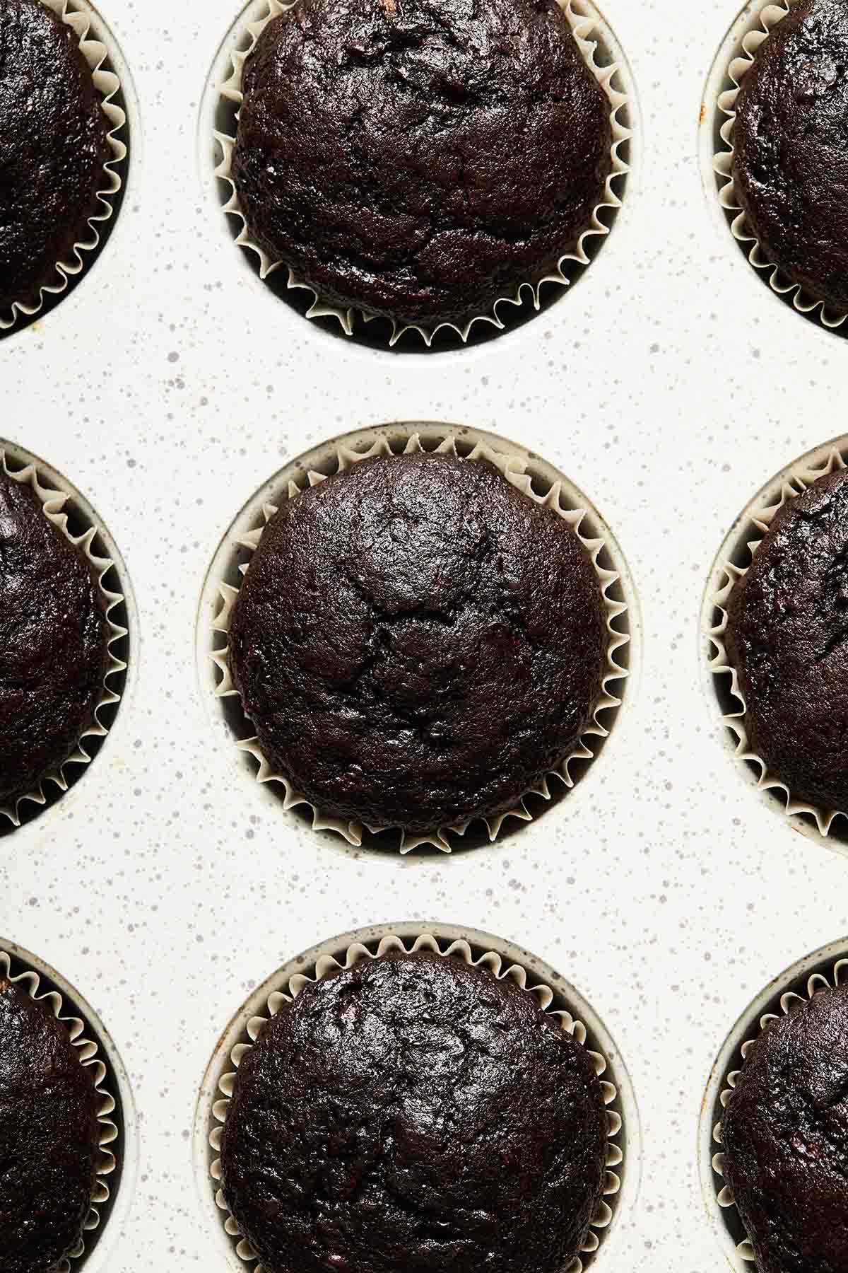 Baked chocolate zucchini cupcakes in a white cupcake pan.