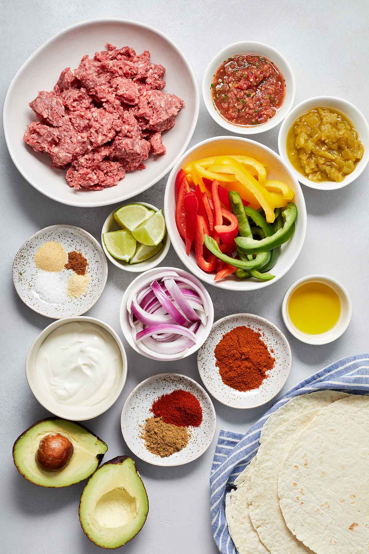 Ingredients to make ground beef fajitas arranged in individual dishes.