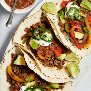 Ground beef fajitas with toppings arranged on a platter.