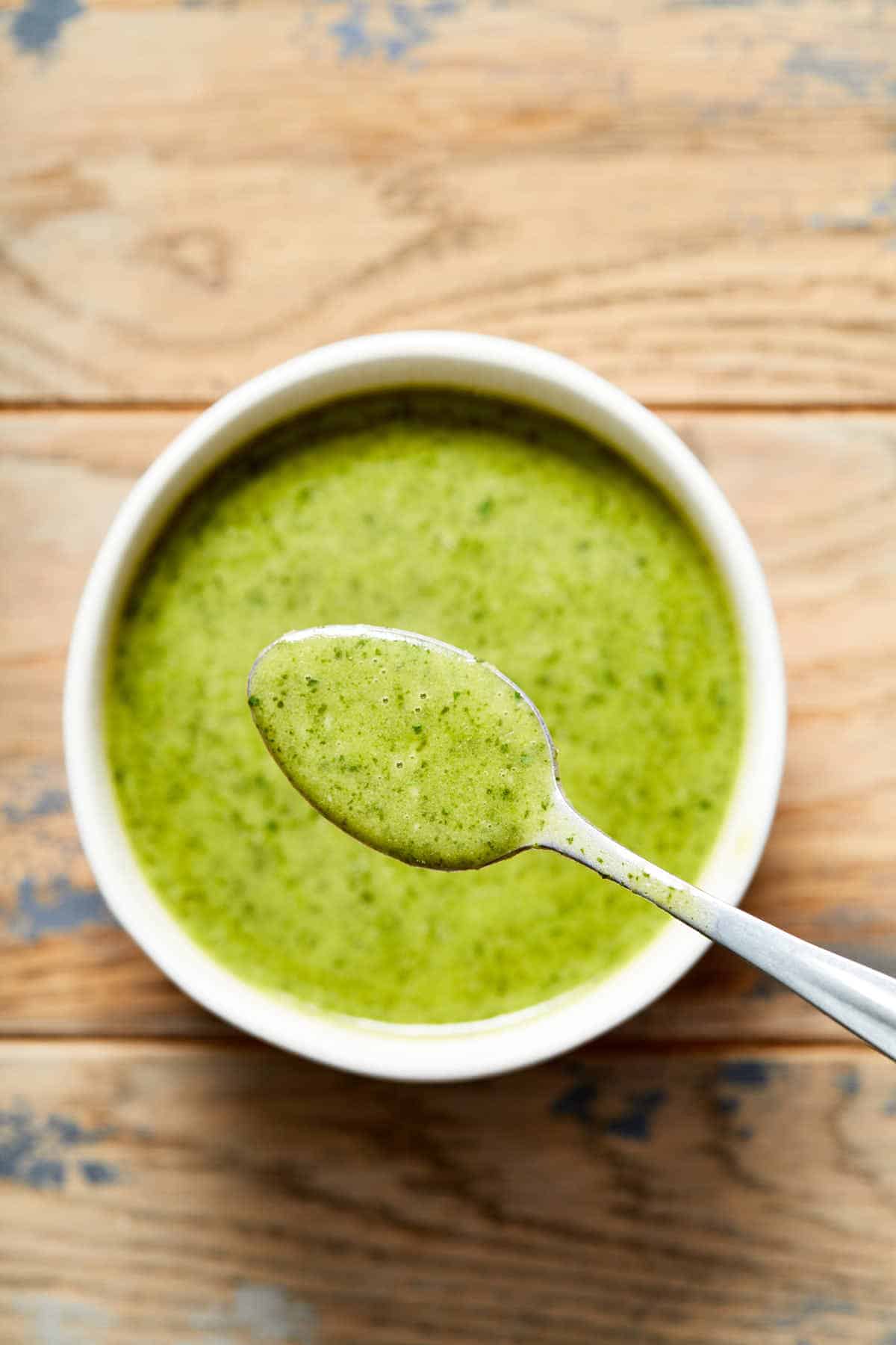 Overhead view of a bowl of jalapeño vinaigrette with a spoonful lifted out to show the texture.