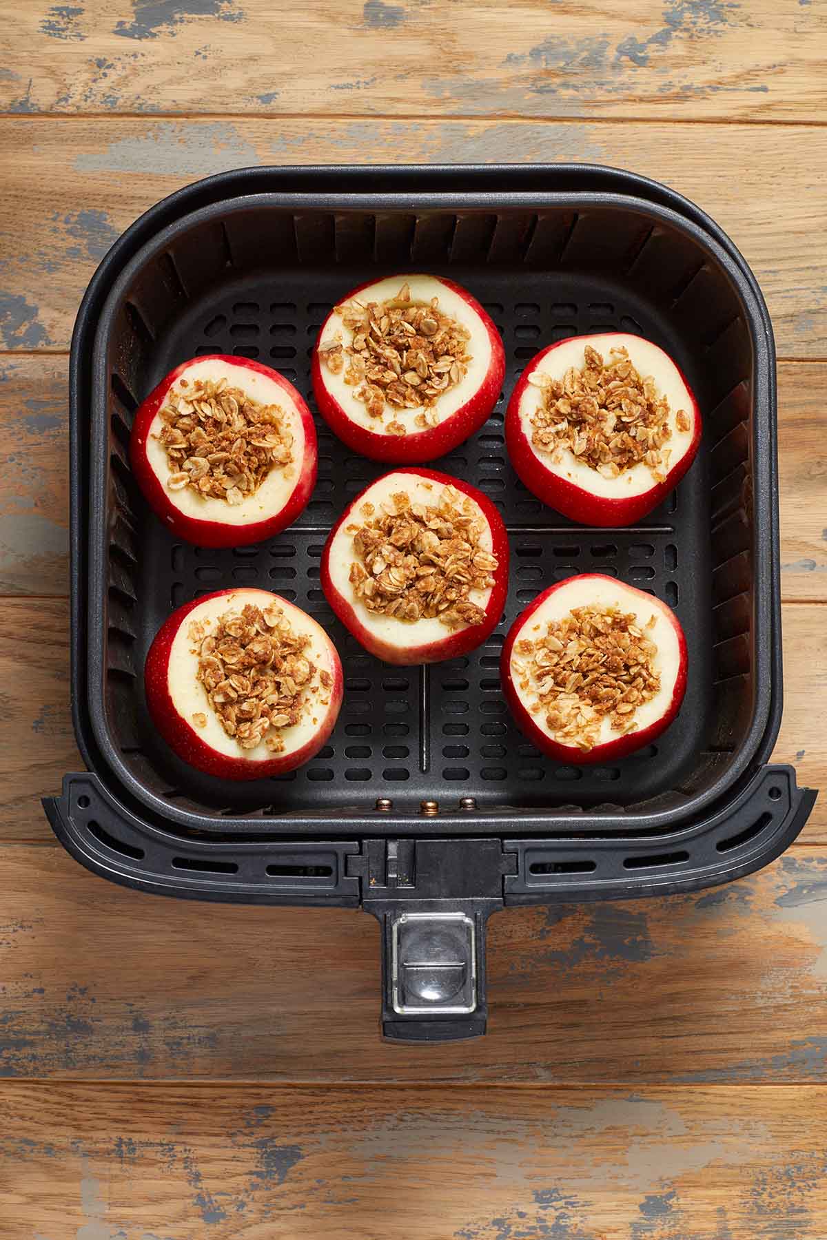 Pre-cooked stuffed apples in the air fryer basket.