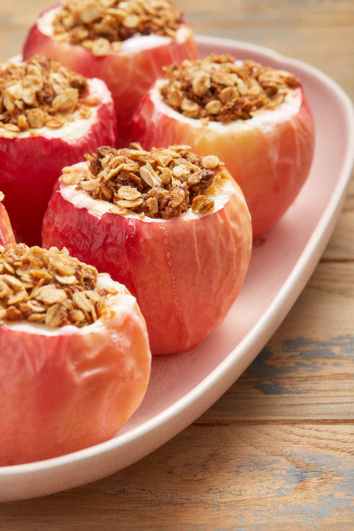Side view of baked apples arranged on a pink platter.