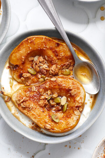 Air fryer pear halves in a blue bowl with yogurt and granola.