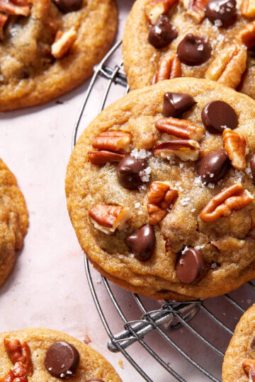 Close up view of a chocolate chip pecan cookie on a wire cooling rack.