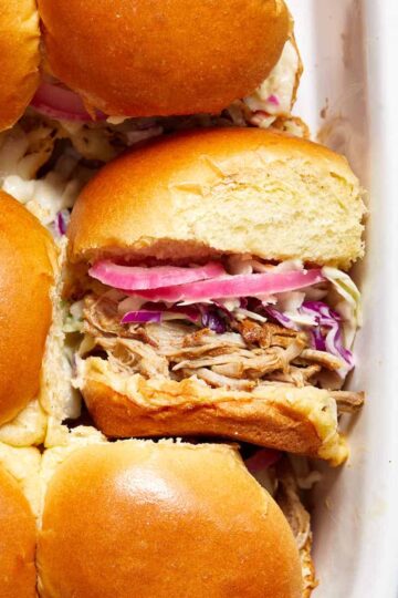 Pulled pork sliders in a dish with one turned on its side.