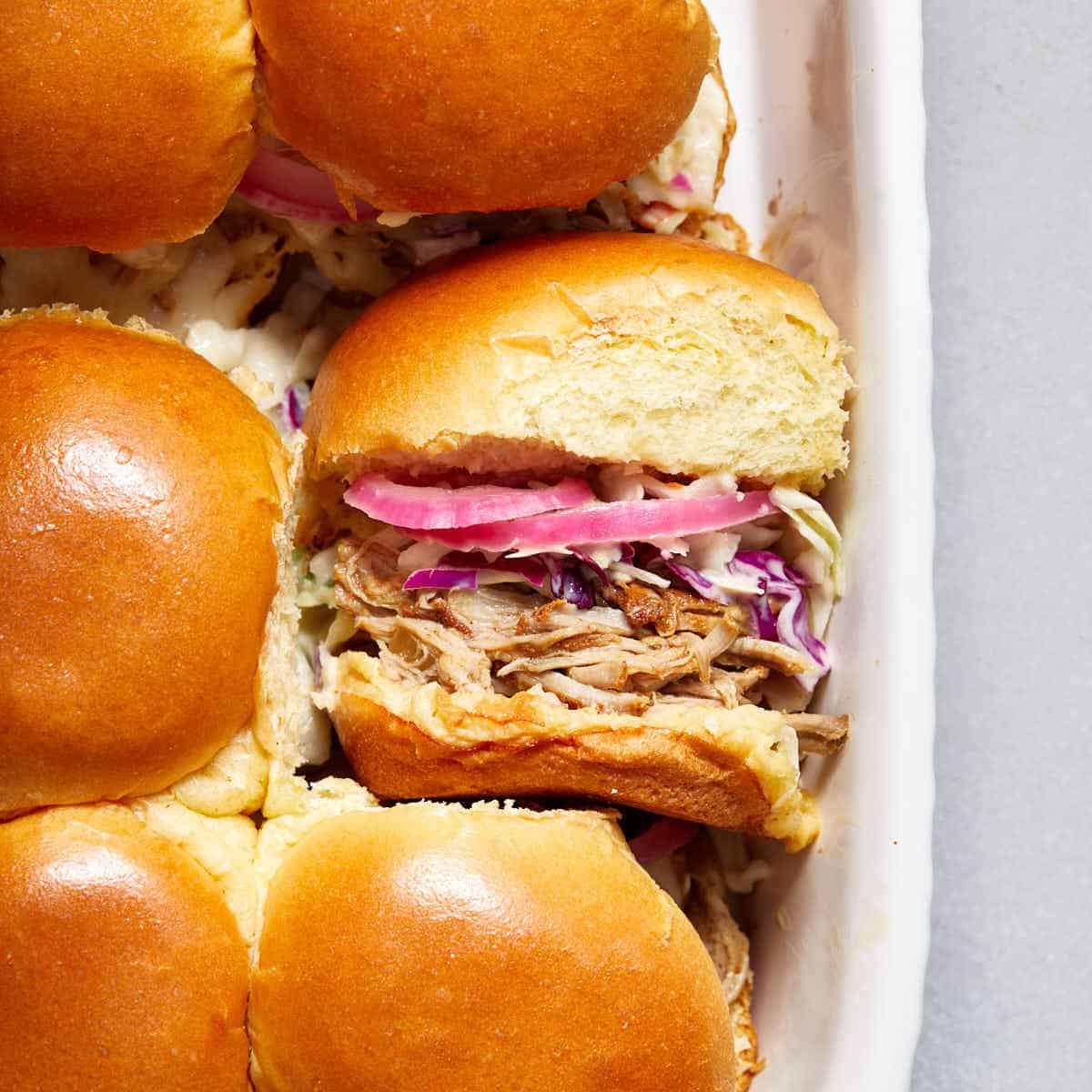 Pulled pork sliders in a dish with one turned on its side.