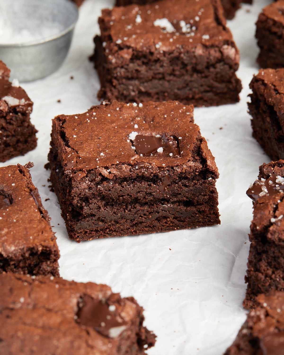 Three-quarter view of brownies arranged on parchment paper.
