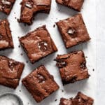 Brownies cut into squares and arranged on crumpled white parchment paper.