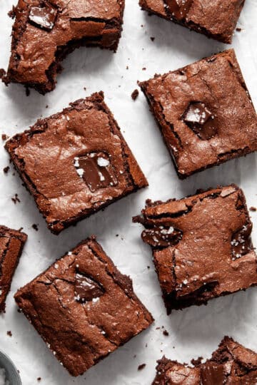 Brownies cut into squares and arranged on crumpled white parchment paper.