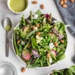 Spring salad served on a plate with dressing on the side.