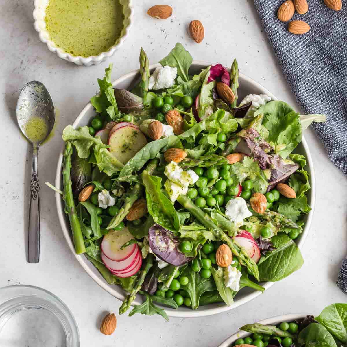 Spring salad served on a plate with dressing on the side.