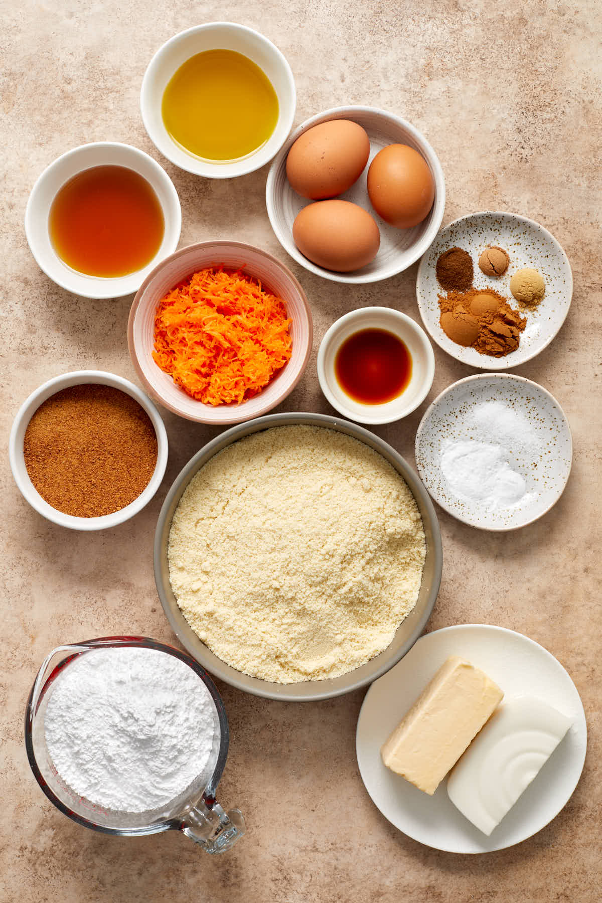 Ingredients to make almond flour carrot cake arranged in individual bowls.