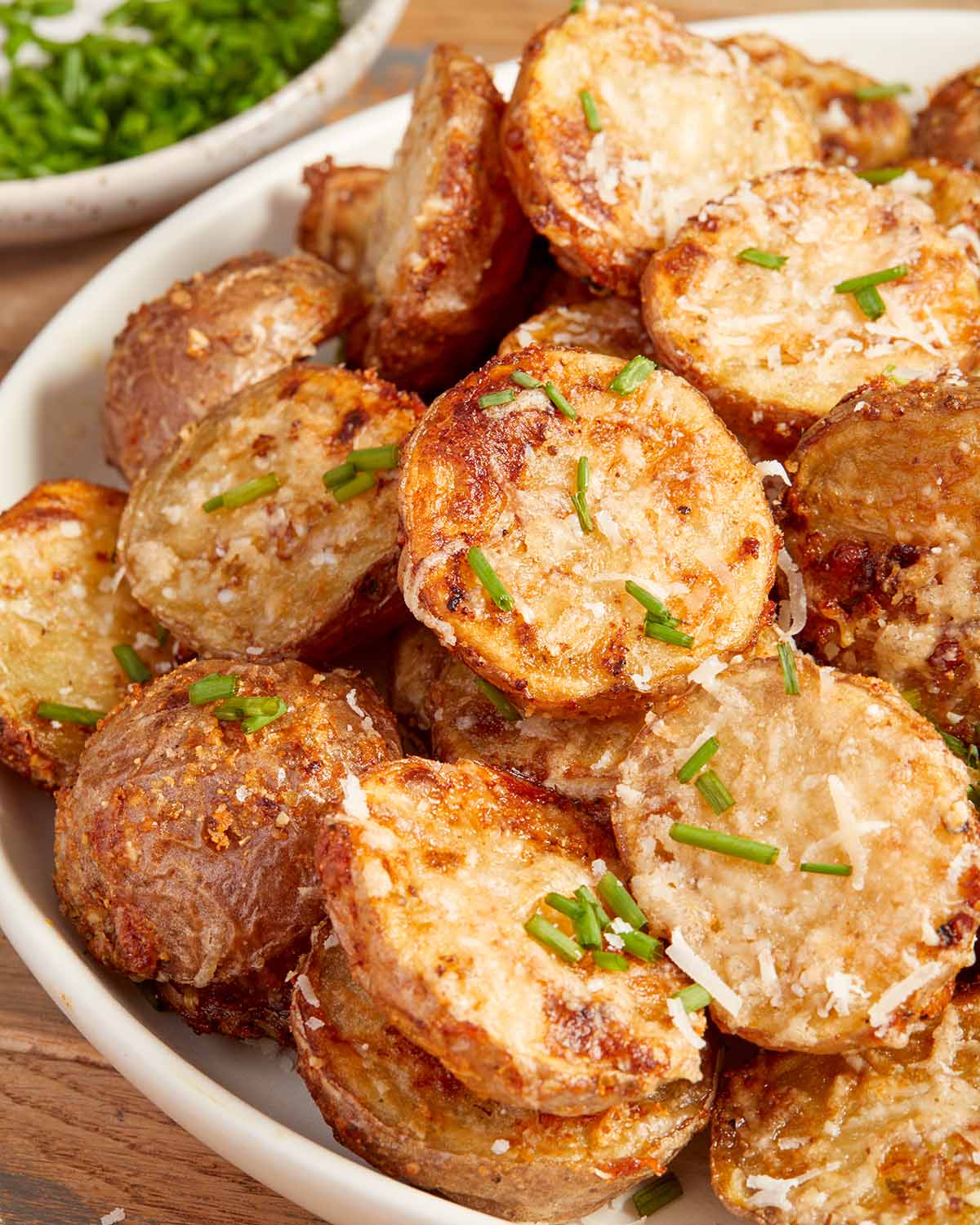Close up view of parmesan potatoes with chopped chives on top.