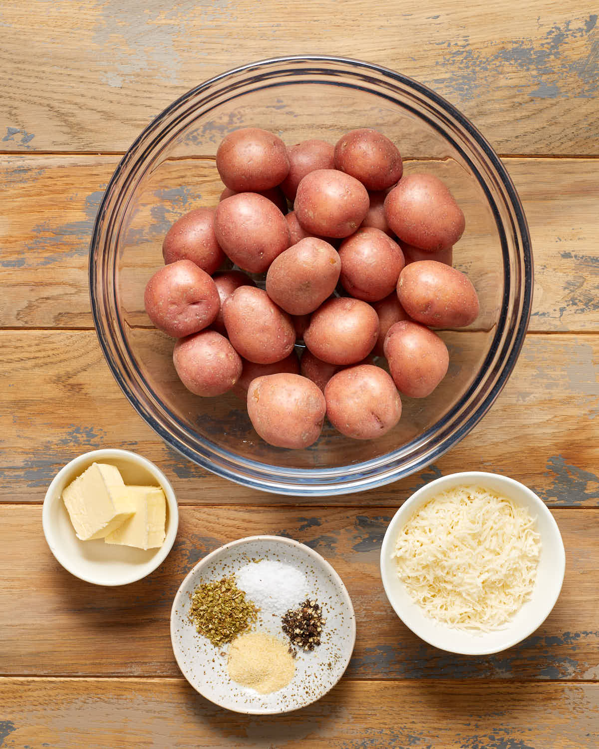 Ingredients to make air fryer parmesan potatoes arranged in individual bowls.