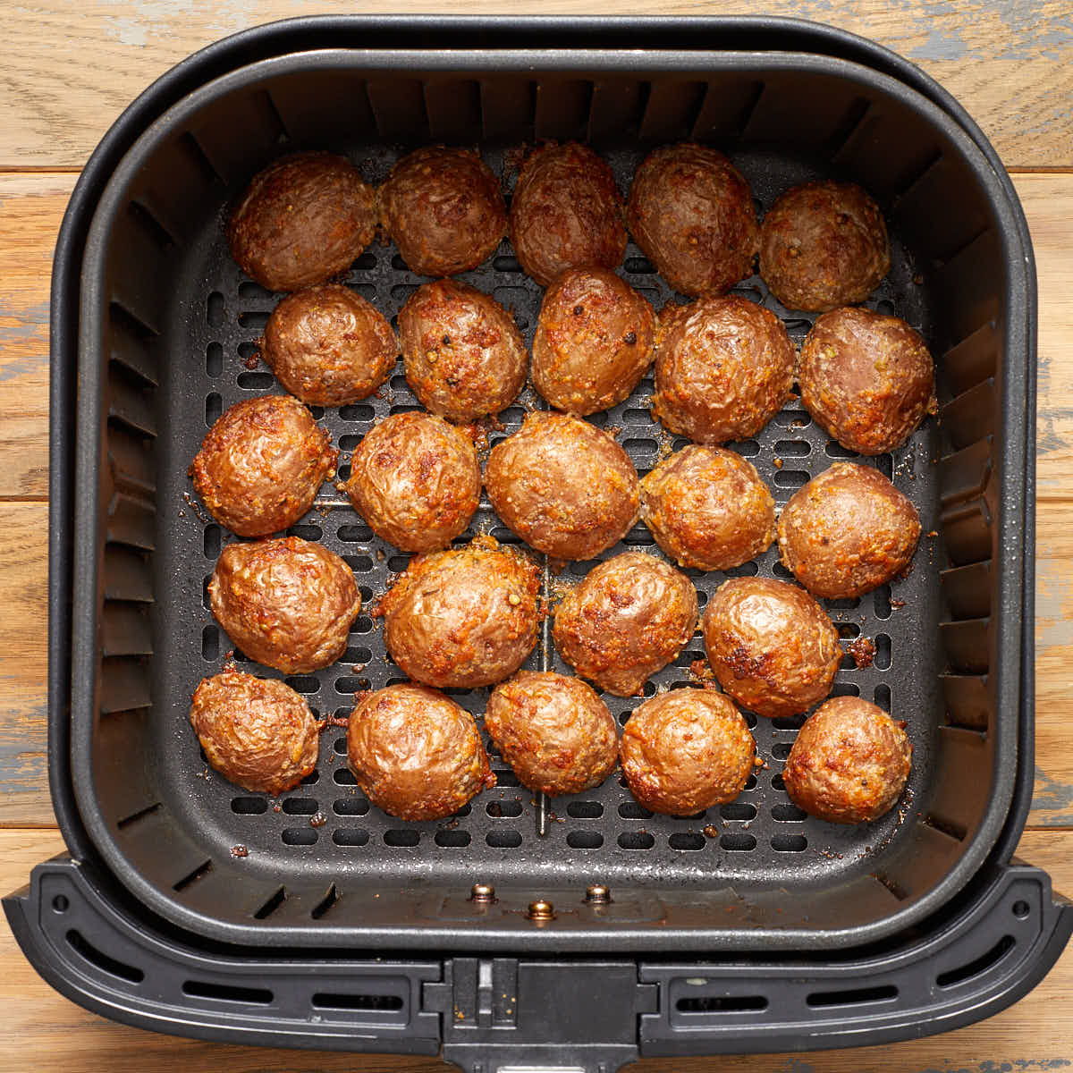 Air fried potatoes cut side down in the air fryer basket.