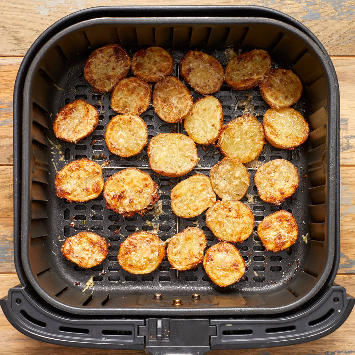 Air fried potatoes cut side up in the air fryer basket.