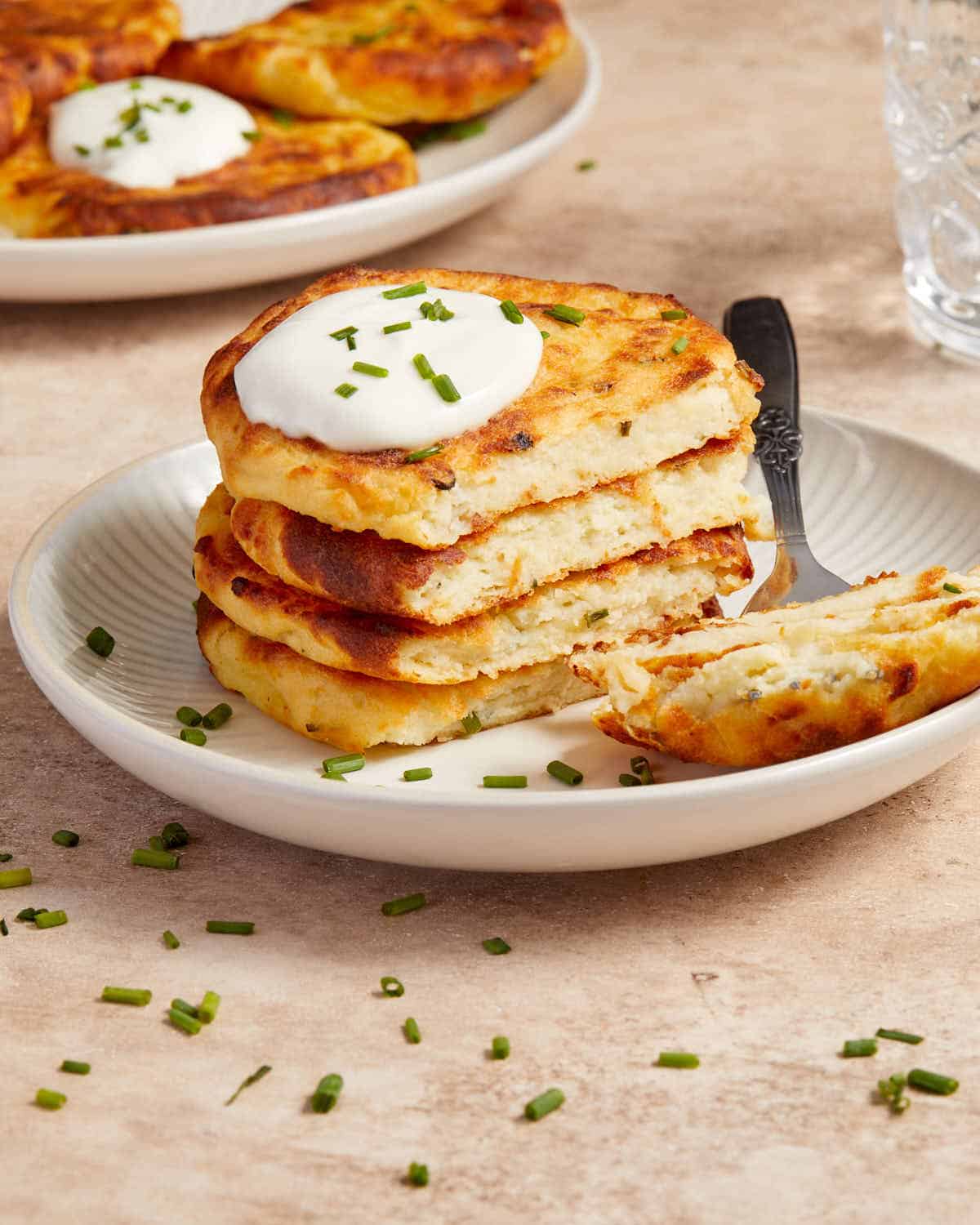 Side view of a stack of potato cakes on a plate with some removed with a fork.