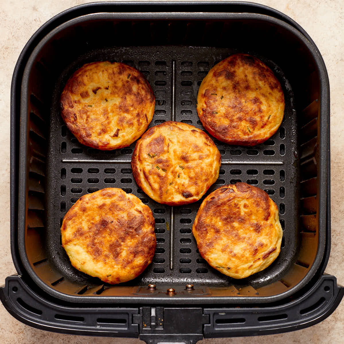 Air fried potato cakes in an air fryer basket.