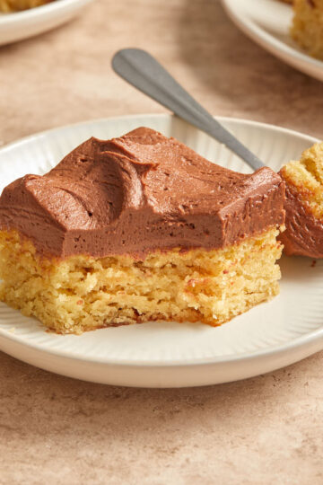 Side view of almond flour banana cake with chocolate peanut butter frosting on a white plate.