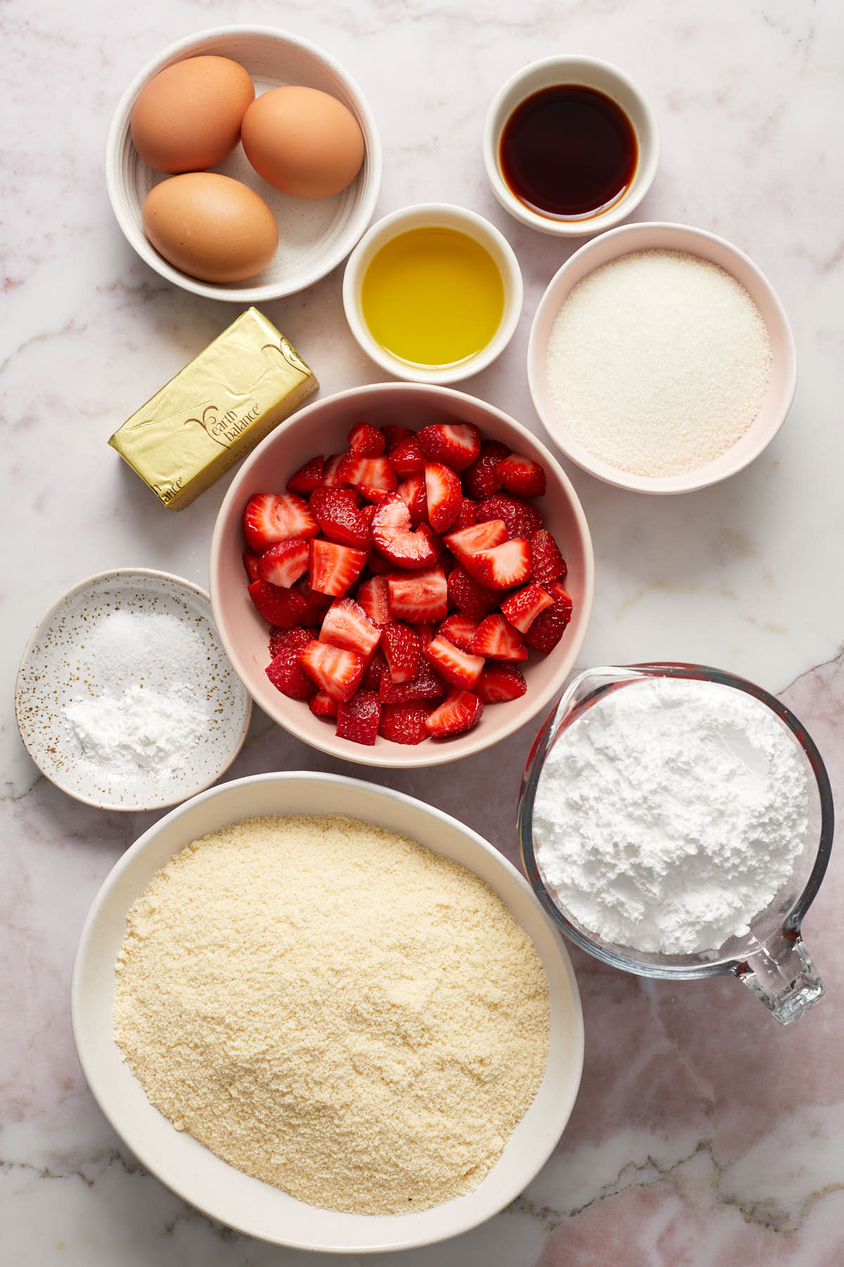 Ingredients to make almond flour strawberry cake arranged in individual dishes.
