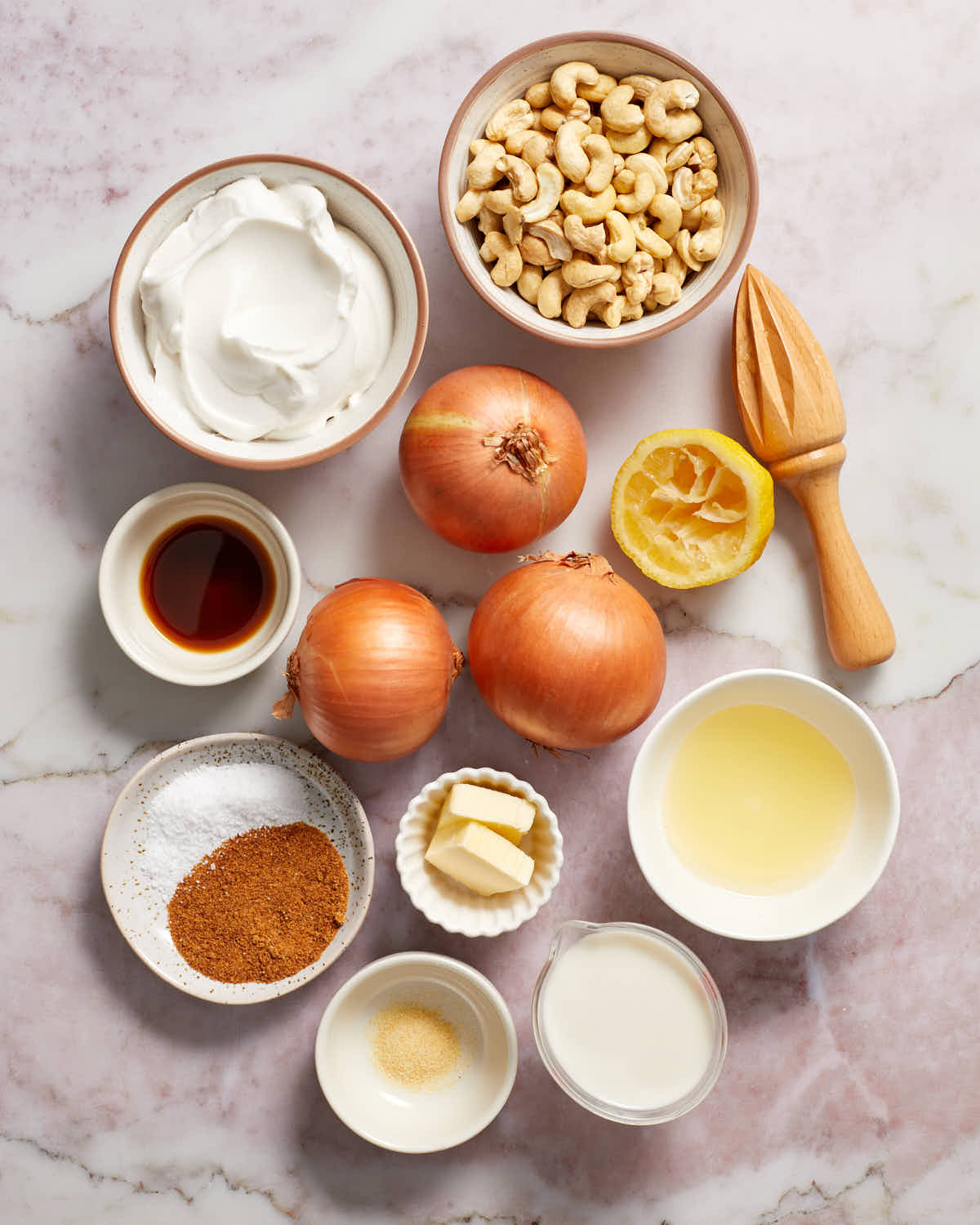 Ingredients to make dairy-free caramelized onion dip arranged in individual bowls with three onions in the middle.