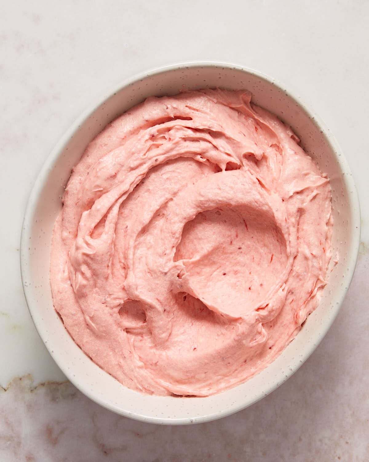 Close up view of strawberry buttercream in a white bowl.
